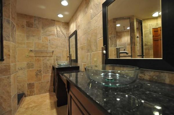 Natural stone on the walls, unusual furniture and a glass sink - a stylish interior