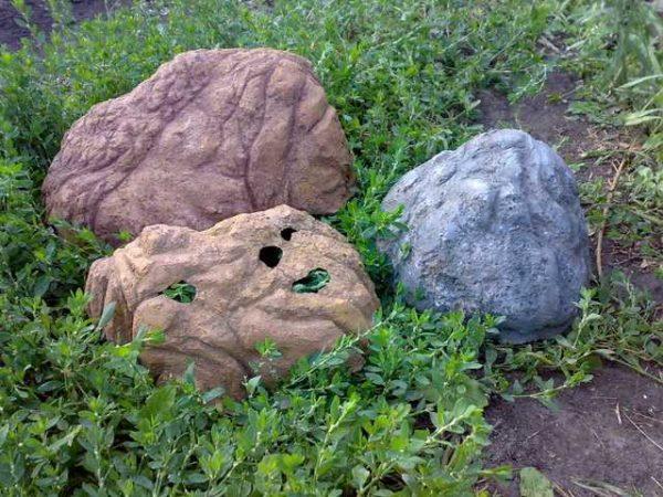 These are stones made of concrete, but they are hollow inside. The base can be molded from clay, covered with several layers of concrete. When it's dry, the clay can be chipped away