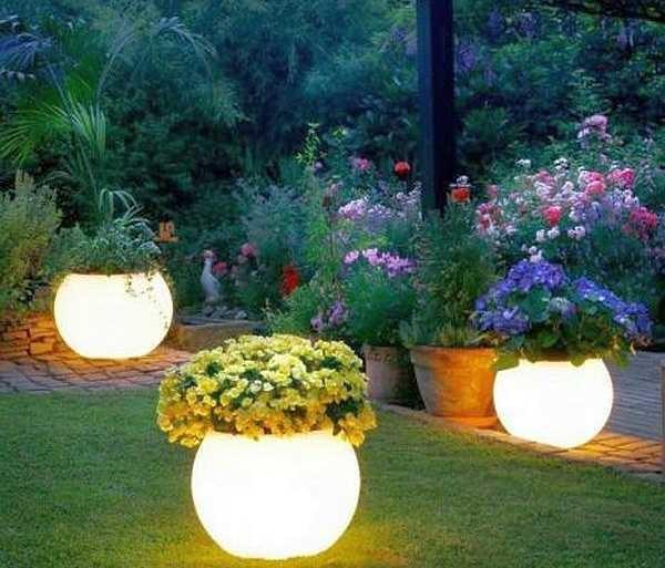 Clay pots painted with luminescent paint in the evening glow as well as lanterns