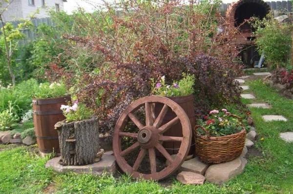 Rustic garden design is easily recognized by the presence of wheels from carts, baskets, ceramic dishes, which is used in the most unexpected hypostasis