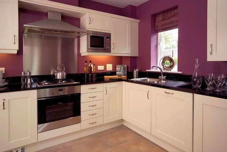 Kitchen with purple walls, black countertop, pale pink cabinet